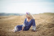 Красива блондинка в блакитній сукні сидить у полі — стокове фото