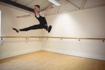 Ballerino saute tout en pratiquant la danse de ballet en studio — Photo de stock