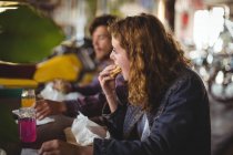 Casal sentado à mesa e comer sanduíche na loja de bicicletas — Fotografia de Stock
