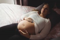 Vista de ángulo alto de la mujer embarazada reflexivo relajarse en el dormitorio en casa - foto de stock