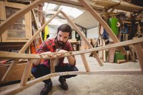 Homme préparant un cadre de bateau en bois au chantier naval — Photo de stock