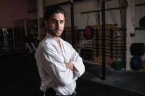 Porträt eines Mannes in Karategi, der mit verschränkten Armen im Fitnessstudio steht — Stockfoto