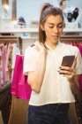 Woman using mobile phone while shopping in boutique store — Stock Photo