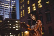 Jovem mulher usando tablet digital na rua à noite — Fotografia de Stock