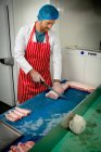 Carnicero rebanando carne en el mostrador de carnicería - foto de stock