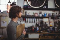 Mécanicien debout avec presse-papiers dans un magasin de vélos — Photo de stock