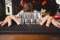 Bartender preparing and lining shot glasses for alcoholic drinks on bar counter at bar — Stock Photo