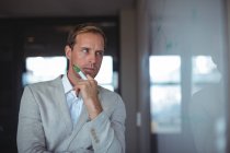 Thoughtful businessman looking at whiteboard at office — Stock Photo