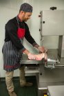 Мясник режет свинину в машине в мясной лавке — стоковое фото