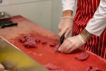Sezione media del macellaio che taglia carne rossa in macelleria — Foto stock