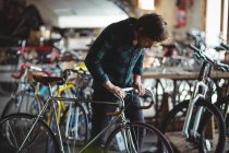 Meccanico esame manubrio bicicletta in officina — Foto stock