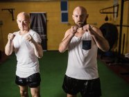 Портрет двух боксеров, стоящих в спортзале и смотрящих в камеру — стоковое фото