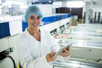 Жіночий персонал використовує цифровий планшет поруч з виробничою лінією на яєчному заводі — стокове фото