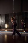 Танцовщица полюса практикует танец полюсов в студии — стоковое фото