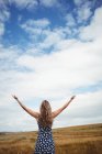Rear view woman standing with arms outstretched in field — Stock Photo