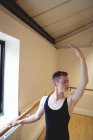 Ritratto di Ballerino che si allunga sulla sbarra mentre pratica la danza classica in studio — Foto stock