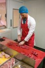 М'ясник рубає червоне м'ясо в м'ясному магазині лічильник — стокове фото