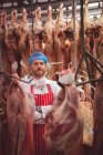 Портрет мясника, стоящего со скрещенными руками в мясной лавке — стоковое фото