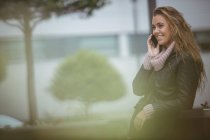 Привлекательная женщина разговаривает по смартфону на улице — стоковое фото