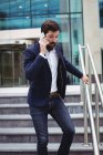 Empresário falando no telefone celular enquanto caminhava nas escadas — Fotografia de Stock