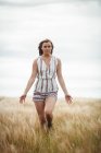 Schöne Frau, die an einem sonnigen Tag durch das Weizenfeld geht — Stockfoto