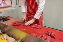 Partie médiane du boucher hachant de la viande rouge à la boucherie — Photo de stock