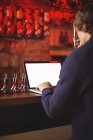 Uomo che utilizza laptop al bancone del bar — Foto stock