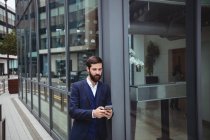 Empresário usando telefone celular fora do escritório — Fotografia de Stock