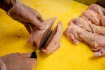 Hands of butcher chopping chicken on work counter in butchers shop — Stock Photo