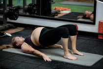 Femme enceinte effectuant des exercices d'étirement dans la salle de gym — Photo de stock