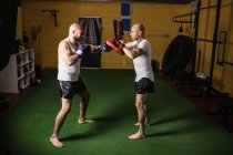 Two athletic thai boxers practicing boxing in gym — Stock Photo