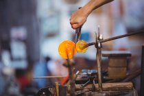 Hand of glassblower shaping a molten glass at glassblowing factory — Stock Photo