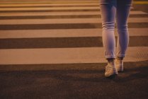 Sezione bassa di donna che cammina sulla zebra attraversando di notte — Foto stock