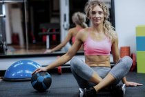 Portrait of beautiful woman holding exercise ball in gym — Stock Photo