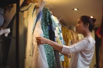 Женщина выбирает одежду из вешалок в бутик-магазине — стоковое фото