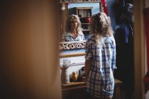 Beautiful woman looking in mirror at home interior — Stock Photo