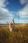 Mulher com as mãos levantadas sobre a cabeça em posição de oração no campo no dia ensolarado — Fotografia de Stock