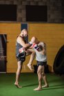 Вид сбоку двух сильных тайских боксеров, практикующих в тренажерном зале — стоковое фото