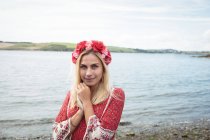 Carefree blonde woman wearing flower tiara and standing near river — Stock Photo