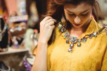 Femme portant un collier vintage dans un magasin d'antiquités — Photo de stock