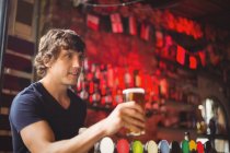 Бар тендер, предлагающий бокал пива клиенту на стойке бара — стоковое фото