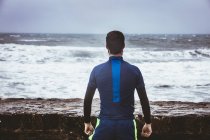 Visão traseira do atleta olhando para o mar — Fotografia de Stock