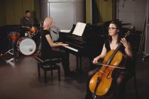 Group of students playing double bass, drum set and piano in a studio — Stock Photo