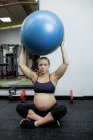 Mujer embarazada haciendo ejercicio con pelota de ejercicio en el gimnasio - foto de stock