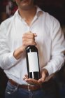 Mid section of bar tender holding a bottle of wine at bar — Stock Photo