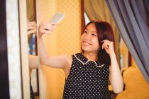 Mujer tomando selfie desde el teléfono móvil en la tienda boutique - foto de stock