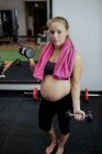Femme enceinte soulevant haltères dans la salle de gym — Photo de stock
