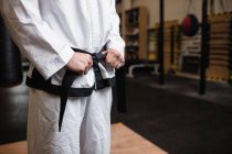 Sección media del hombre en kimono karate de pie en el gimnasio - foto de stock