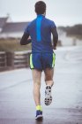 Visão traseira do atleta correndo na estrada durante o dia — Fotografia de Stock