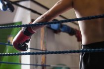 Abgeschnittenes Bild eines Boxers, der sich an Seile des Boxrings lehnt — Stockfoto